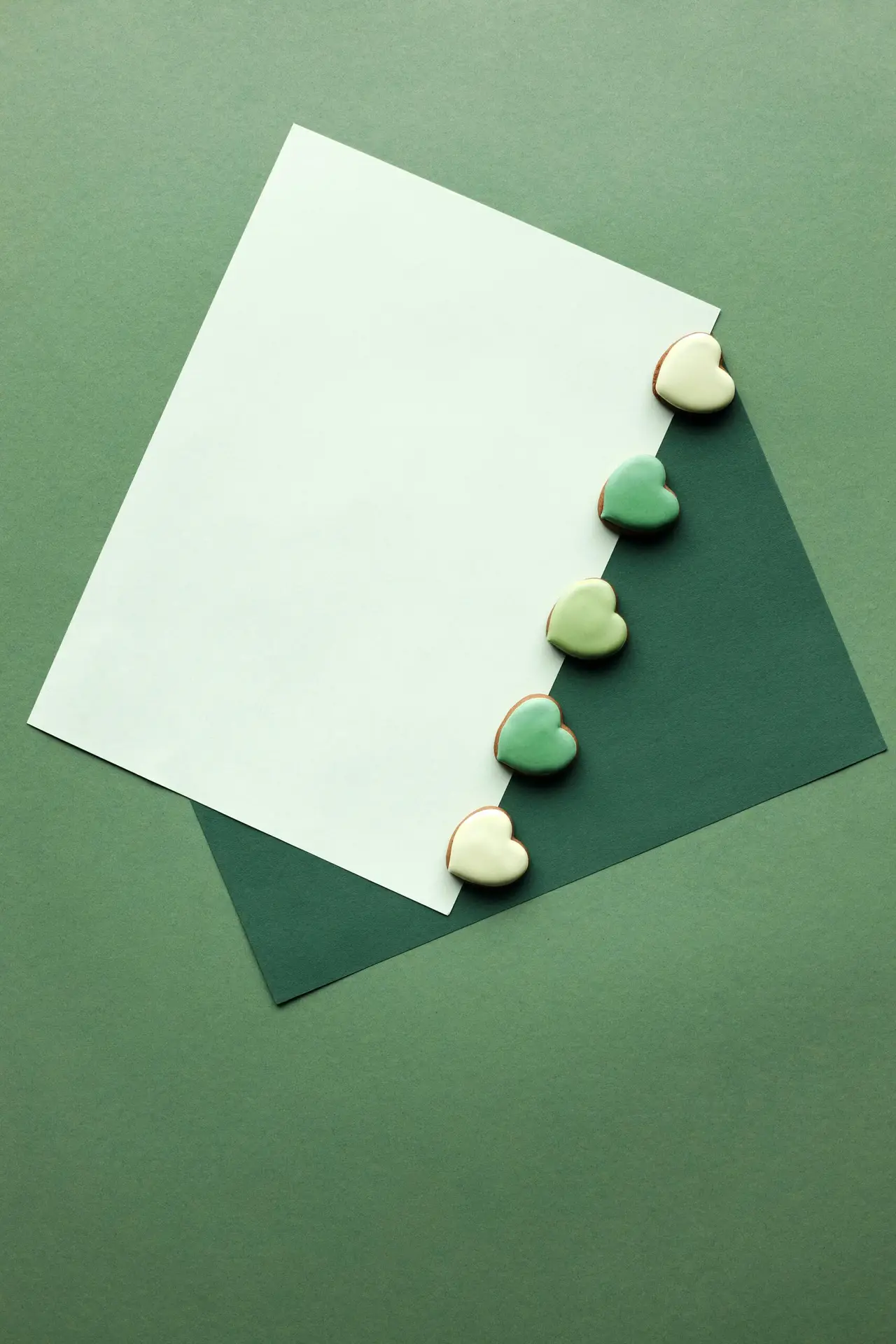 A minimalist layout featuring green heart-shaped decorations on layered paper, perfect for St. Patrick's Day themes.